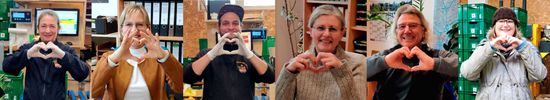 KI generiert: Das Bild zeigt sechs Personen, die jeweils mit ihren Händen ein Herzzeichen formen. Diese Menschen lächeln und stehen in einem offenbar beruflichen Umfeld mit Regalen und Ordnern im Hintergrund.