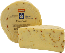KI generiert: Das Bild zeigt einen runden Laib Fen-Chili-Käse der Käserei Höhenberg mit einer abgeschnittenen Scheibe. Der Käse enthält Chilistecken und ist ein Produkt der Marke Demeter.