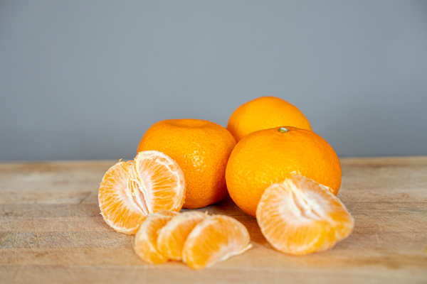 KI generiert: Mandarinen und Mandarinenstücke auf einem Holztisch.