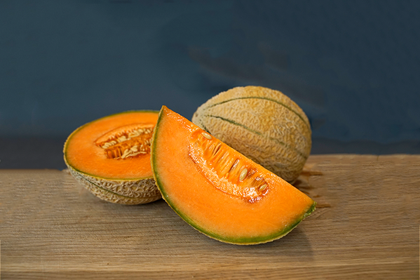KI generiert: Eine ganze und eine angeschnittene Cantaloupe-Melone auf einem Holztisch.