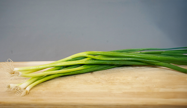 KI generiert: Ein Bund Frühlingszwiebeln liegt auf einem Holzbrett.