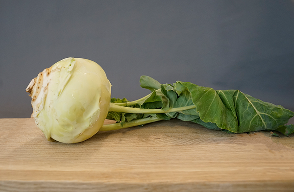 KI generiert: Ein Kohlrabi mit Blättern liegt auf einem Holzbrett.