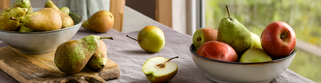 KI generiert: Das Bild zeigt mehrere Pastinaken, frische und in Scheiben geschnittene, auf einer hellen Holzoberfläche. Daneben liegen einige grüne Blätter zur Dekoration.