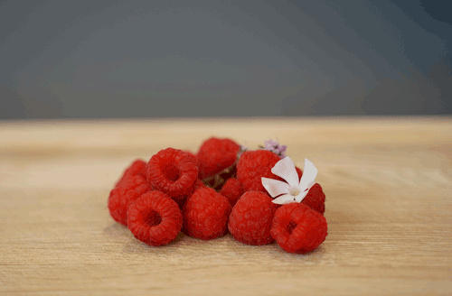 KI generiert: Ein paar Himbeeren mit dekorativen Blumen auf Holz.