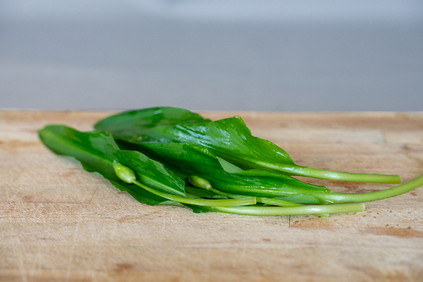 KI generiert: Einige frische Bärlauchblätter liegen auf einem Holzbrett.