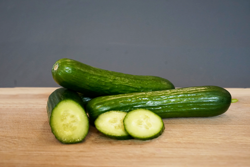 KI generiert: Einige Gurken, teilweise aufgeschnitten, liegen auf einem Holzbrett.