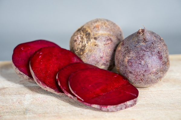 KI generiert: Rote Bete, ganz und in Scheiben geschnitten, auf einem hellen Untergrund.