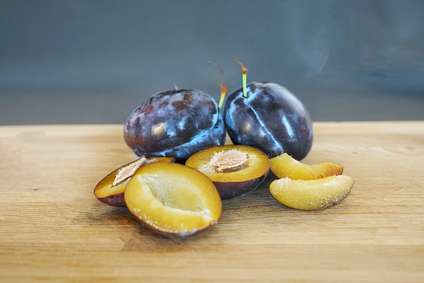 KI generiert: Frische und geschnittene Pflaumen auf einem Holzbrett.