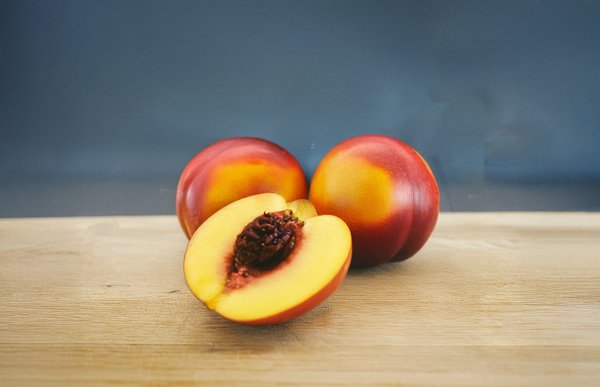 KI generiert: Drei Nektarinen auf einem Holzbrett, eine davon ist halbiert sichtbar.