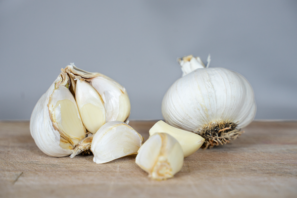 KI generiert: Knoblauchzehen und -knolle auf einem hölzernen Untergrund.