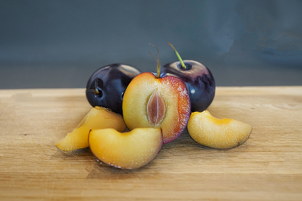 KI generiert: Pflaumen auf einem Holzbrett, teilweise aufgeschnitten.