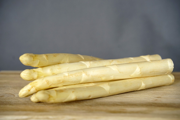 KI generiert: Mehrere weiße Spargelstangen liegen auf einem Holztisch.