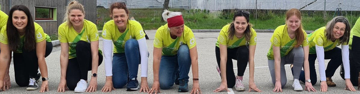 KI generiert: Das Bild zeigt sieben Frauen in gelben Trikots, die in Startposition an einem Rennen teilnehmen wollen. Sie stehen auf einer asphaltierten Fläche und lächeln in die Kamera.