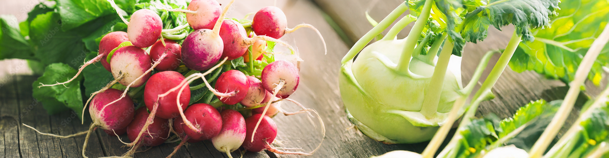 KI generiert: Das Bild zeigt mehrere Pastinaken, frische und in Scheiben geschnittene, auf einer hellen Holzoberfläche. Daneben liegen einige grüne Blätter zur Dekoration.