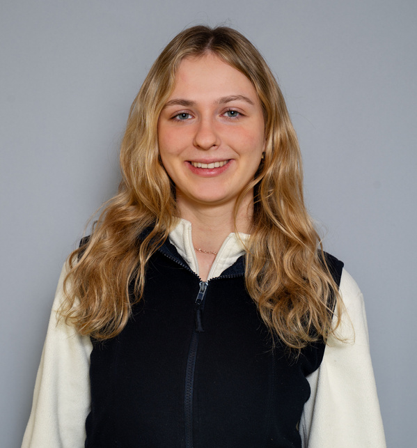 KI generiert: Eine Frau lächelt in die Kamera vor einem grauen Hintergrund.