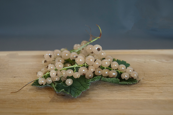 KI generiert: Weiße Johannisbeeren auf einem Holztisch vor dunklem Hintergrund.
