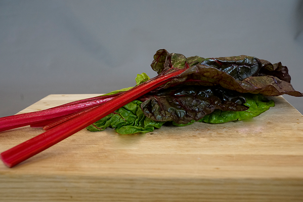 KI generiert: Ein Bündel roter Mangoldblätter liegt auf einem Holzbrett.
