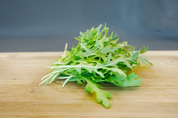 KI generiert: Ein Bündel Rucola liegt auf einem Holzbrett.