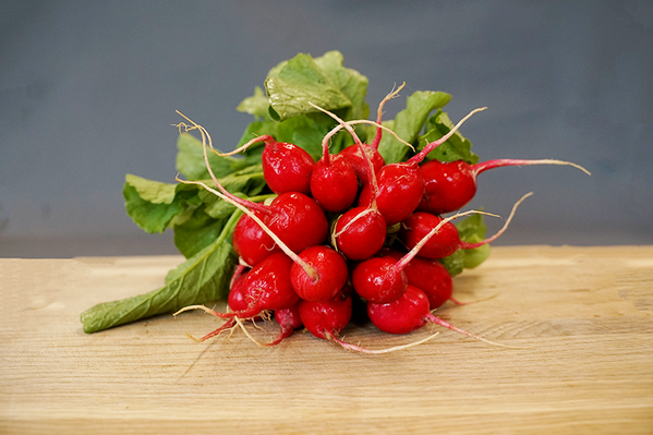 KI generiert: Ein Bund frischer, leuchtend roter Radieschen auf einem Holzbrett.